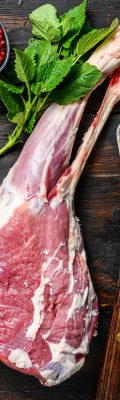Whole raw leg of lamb. Fresh organic meat. Dark wooden background. Top view.